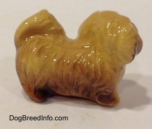 The right side of a brown and tan figurine of a Pekingese puppy. The figurine has fine hair grooves.
