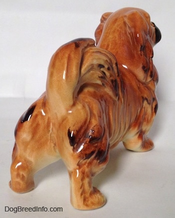 The back right side of a brown and tan with black figurine of a Pekingese.