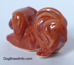 The back left side of a brown Pekingese figurine. It is hard to tell the difference between the ears of figurine from its head.