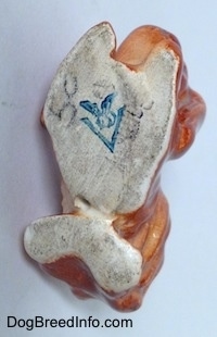 The underside of a brown Pekingese figurine. The figurine has a blue full bee inside the V Goebel W. Germany logo stamped on it.