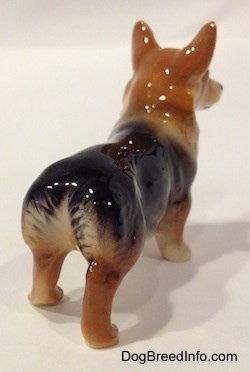 The back right side of a black and tan Pembroke Welsh Corgi figurine. The figurine does not have a tail.