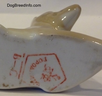 The underside of a Pharoah Hound figurine and it has a large read stamp on the bottom.