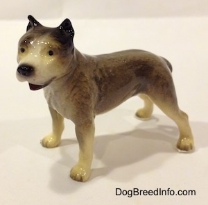 A figurine of a grey, black and white Pit Bull Terrier figurine. The figurine has black circles for eyes.