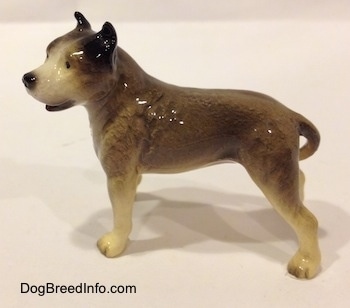 The left side of a grey, black and white Pit Bull Terrier figurine. The figurine has long legs.