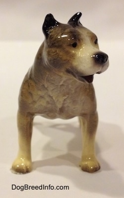 A black, gray and white Pit Bull Terrier figurine. The figurine has its mouth open.