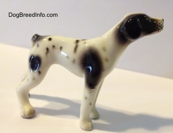 The front right side of a white and black spotted Pointer figurine. It is hard to differentiate between the ears and head of the figurine.