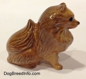 The right side of a sitting brown Pomeranian figurine. The figurine has a tail that is sitting on its back.