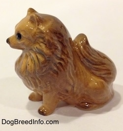 The left side of a brown figurine sitting Pomeranian. The figurine has short legs.