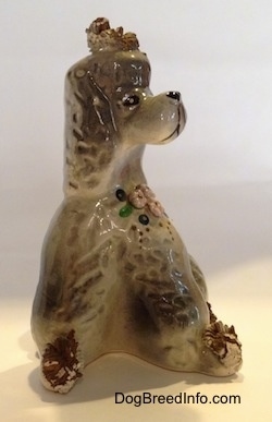 A figurine of a ceramic spaghetti Poodle. The figurine has detailed eyes and a black circle for eyes.