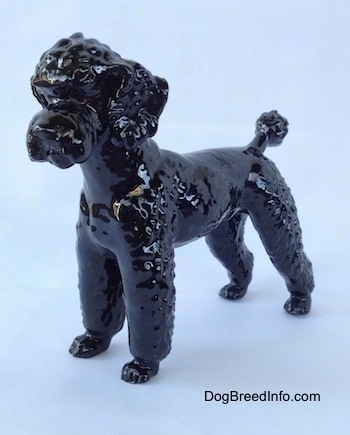 The front left side of a figurine of a black Poodle. The figurine has fine hair details.
