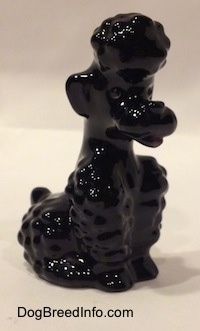 The front right side of a black Poodle figurine that is in a sitting position. The figurines mouth is open.