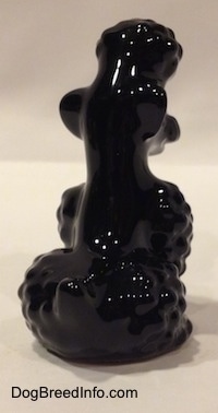 The back right side of a black Poodle sitting figurine. The figurine has a hair clump on top of its head.