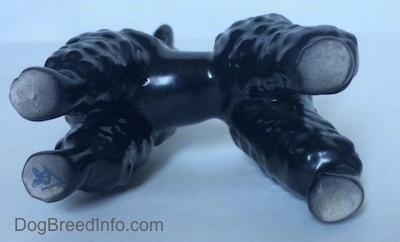 The underside of a black Poodle figurine. On its front right leg it has the bee logo of Goebel W.Germany on it.