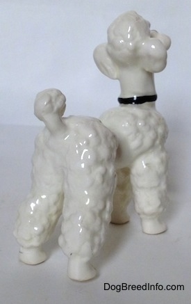 The back right side of a figurine of a white Poodle. The figurine has a small tail with a large hair poof at the end of it.