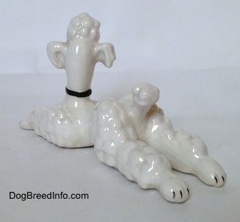 The back left side of a white Poodle in a lying pose figurine. The ears of the figurine are attached to its head