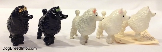 Five different color variations of a figurine of a Poodle with a bow in its hair. The figurines have a large poof of hair on its upper body.