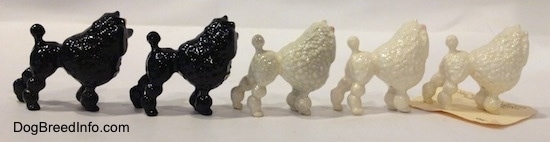 The right side of a figurine of five different color variations of a Poodle with a bow in its hair. The figurine has large poofs up and down its legs.