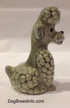 The right side of a gray figurine of a Poodle sitting. The figurine has a hair pile on its head.