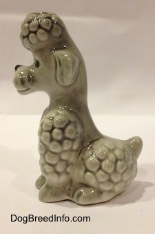 The left side of a gray Poodle sitting figurine. The figurine has short legs.