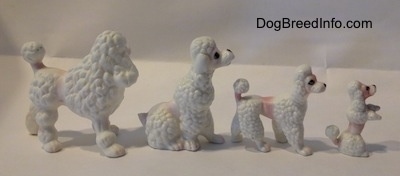 The right side of a family of four bone china Poodle puppy figurines. The figurines have black circles for eyes.