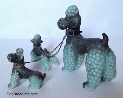The left side of three Porcelain Poodle figurines that are chained together. All of the Poodles have a hair poof on there heads.