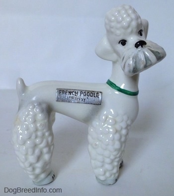 The right side of a white Poodle with a green collar figurine. There is a sticker on its right side that reads 'French Poodle'.