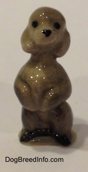 A miniature gray Poodle figurine that is in a begging pose.