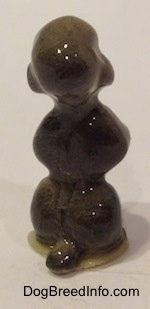 The back of a miniature gray Poodle figurine that is in a begging pose. The figurine has a short tail.