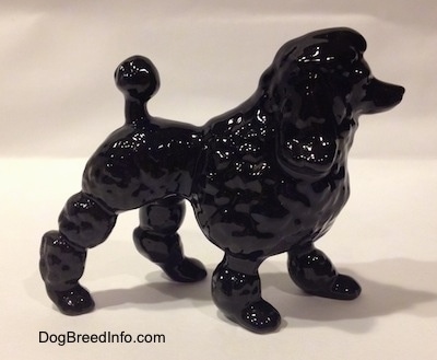 The right side of a figurine of a black porcelain Poodle. The figurines ears are hard to differentiate from its head.