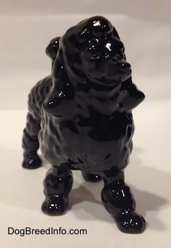 A black porcelain Poodle figurine. It is hard to see the features on the figurines face.