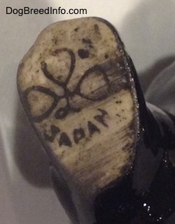 Close up - On the underside of a black porcelain Poodle figurine is the logo stamp that reads 'Japan'.
