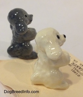 The right side of figurines of a Poodle puppy in a begging pose. The Figurines have big black circles for eyes.