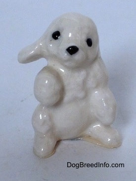 A figurine of a white Poodle puppy in a begging pose.