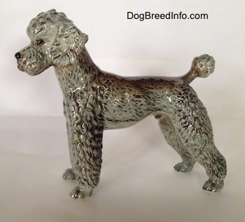 The right side of a black, gray and brown Poodle figurine. The figurine has a poof at the end of its small tail.