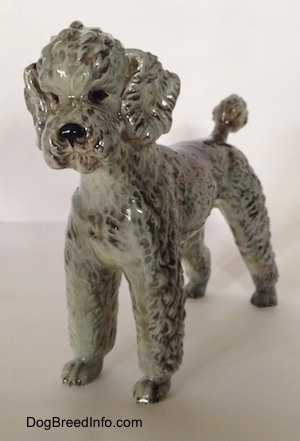 A black, gray and brown Poodle figurine. The figurine has black circles for eyes.