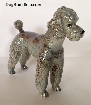 The front right side of a black, gray and brown figurine of a Poodle. The figurine has tiny paws.
