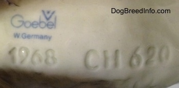 Close up - The underside of a Poodle figurine. On the underside is the stamped logo of Goebel W. Germany and under that is an engraving of the year'1968' and next to the is an engraving of a series of numbers and letters 'Ch 620'.
