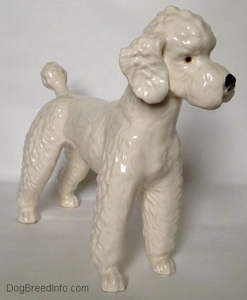 The front right side of a white Poodle figurine. The figurine has detailed hairy legs.