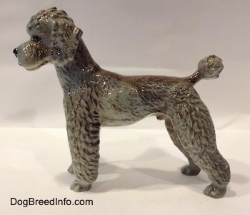 The left side of a black, gray and brown Poodle standing figurine. The figurien is glossy.