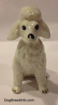 A white Poodle figurine that is in a seated position. The figurine has a mouth that is painted slightly open.