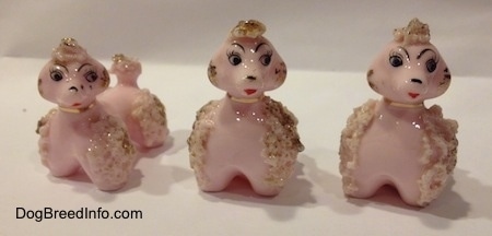 Three Vintage pink porcelain Spaghetti figurines of Poodle puppies. The figurines have there mouths painted open.