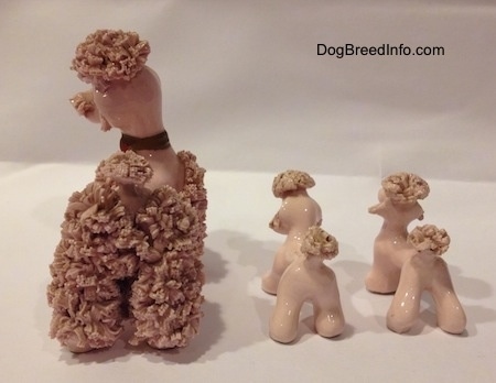 The back of three porcelain pink spaghetti figurines. The tails of the figurines have rough bristles for tails and on top of there heads.