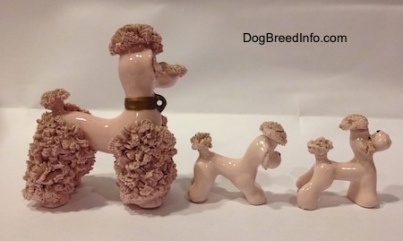 The right side of three figurines of porcelain pink spaghetti Poodles. One puppy figurine is looking down and the other is looking up.