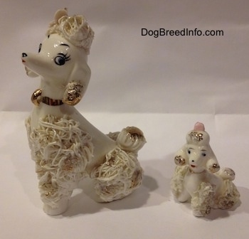 The front left side of two porcelain white spaghetti figurines. The Adult figurine has very detailed eyes. The puppy figurine has black circles for eyes.