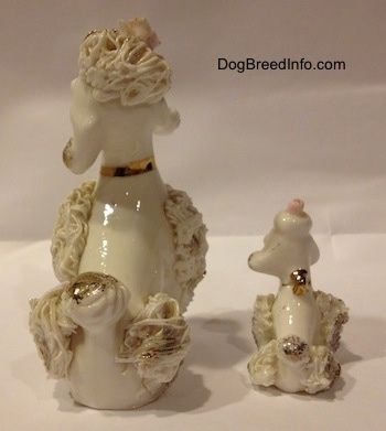 The back of two white spaghetti porcelain figurines of Poodles. The figurines have small poofy tails that are gold at the end.