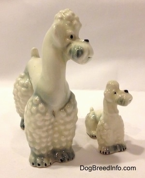 The front right side of two white spots of gray figurines of Poodles. The figurines hace black circles for noses.