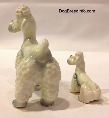 The back left side of two white Poodle figurines with spots of gray. The ears of the figurines are hard to differentiate from the head.