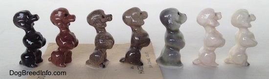 The right side of seven different color variations of a Poodle puppy figurine in a begging pose. The figurines are glossy.