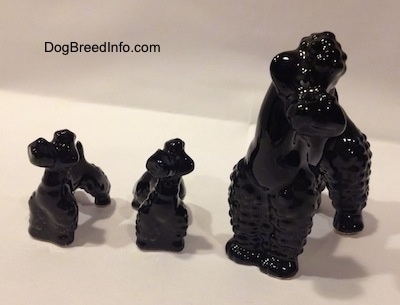 There are three black Poodle figurines. Two puppy figurines and an adult one. The figurines are glossy/