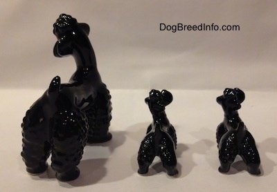 The back of three black Poodle figurines. The figurines have lumpy legs.